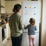 Mamma e bimbo di spalle guardano insieme il tabellone sul frigo